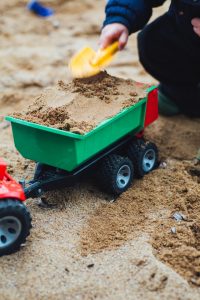 child filling a toy truck with sand